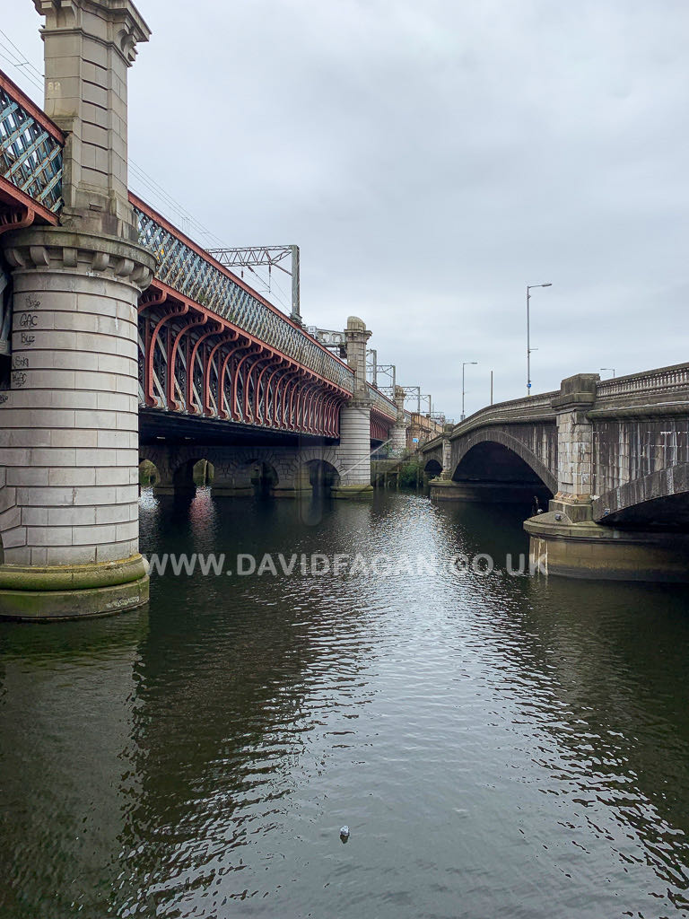 A red lattice railway bridge carried on stone piers over the river